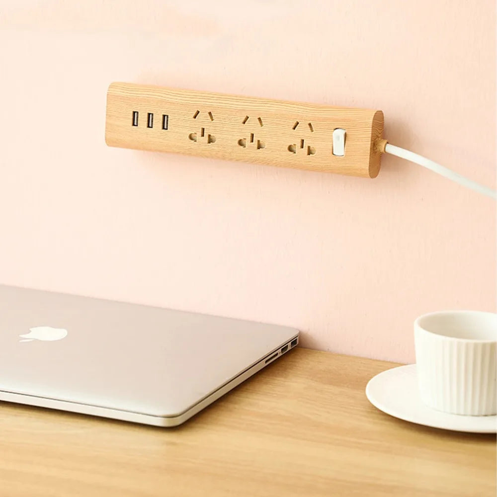 Multiprise en bois avec 3 prises et 3 ports USB fixée sur mur rose au-dessus d'un bureau en bois