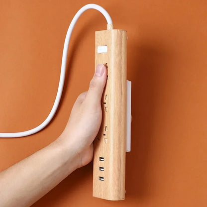 Multiprise en bois avec prises et ports USB, tenue à la main sur fond orange
